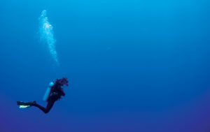 scuba diver swims over reef