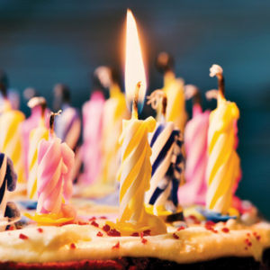 closeup of some unlit candles and just a lit candle after blowing out the cake, filtered